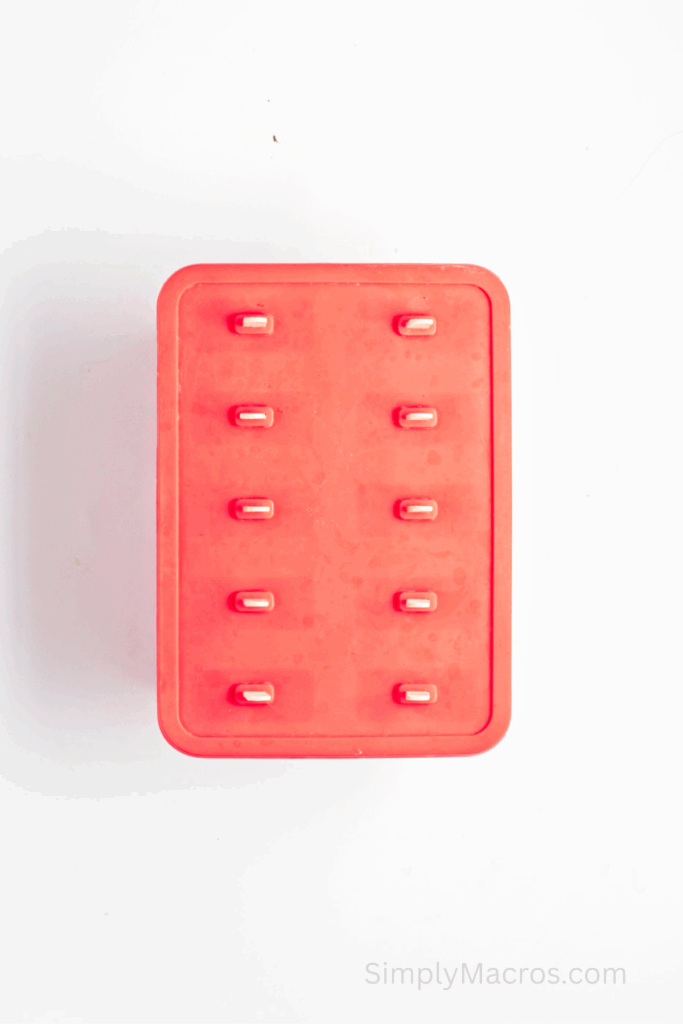 Popsicle mold with top and sticks placed on the mold.
