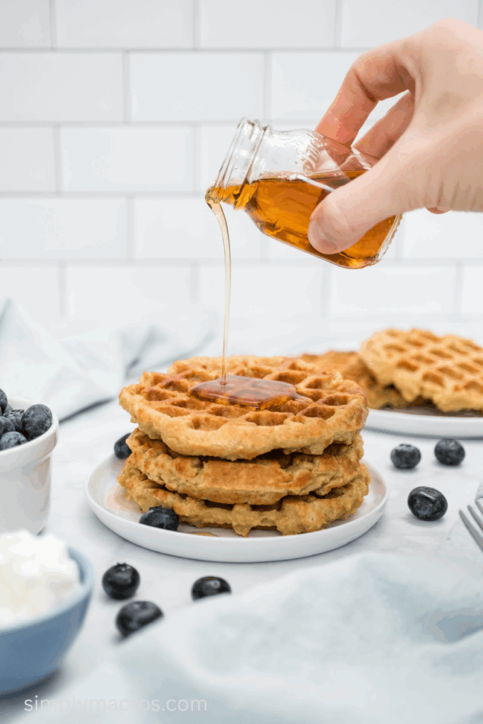 Maple syrup being poured over cottage cheese waffles.