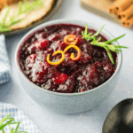 Homemade cranberry sauce in a serving bowl topped with garnish.