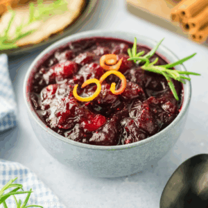 Homemade cranberry sauce in a serving bowl topped with garnish.