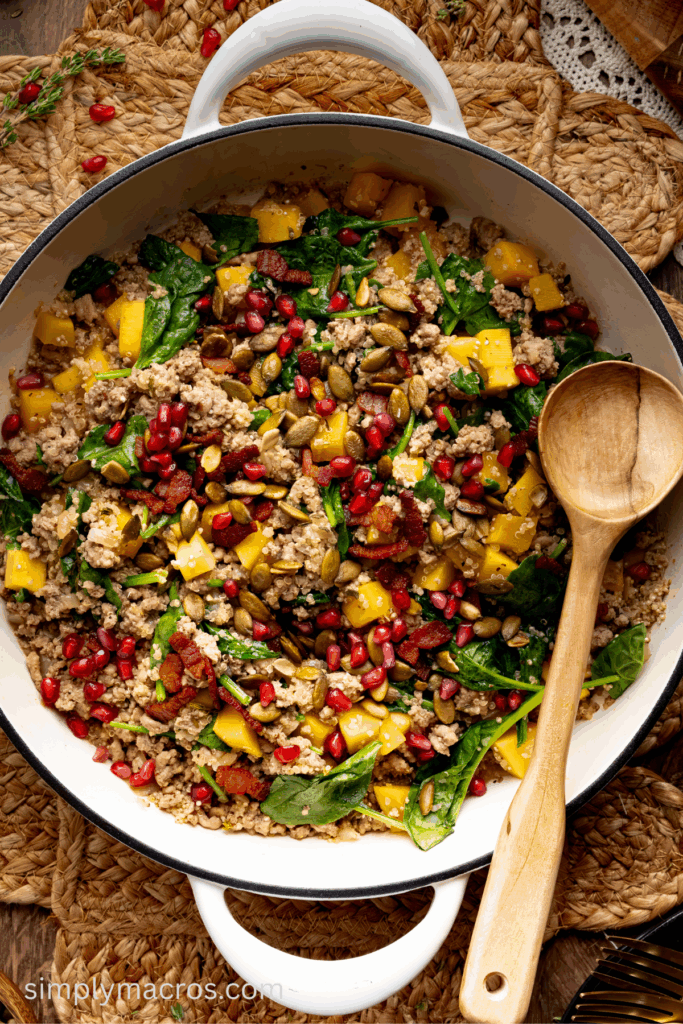 Wooden spoon in the skillet of the turkey quinoa dish with butternut squash.