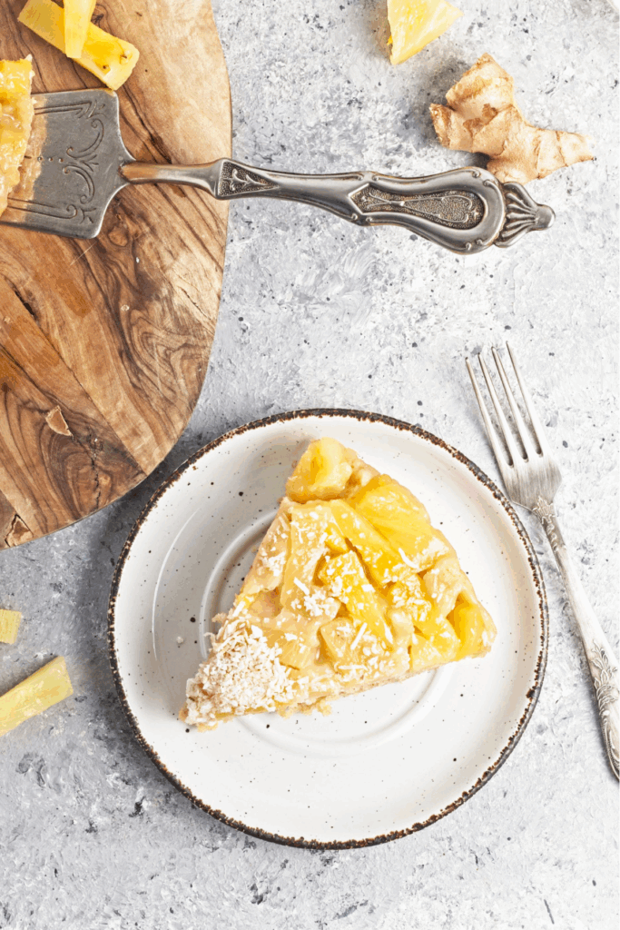 Vegan pineapple upside down cake on a plate with coconut flakes sprinkled on top.