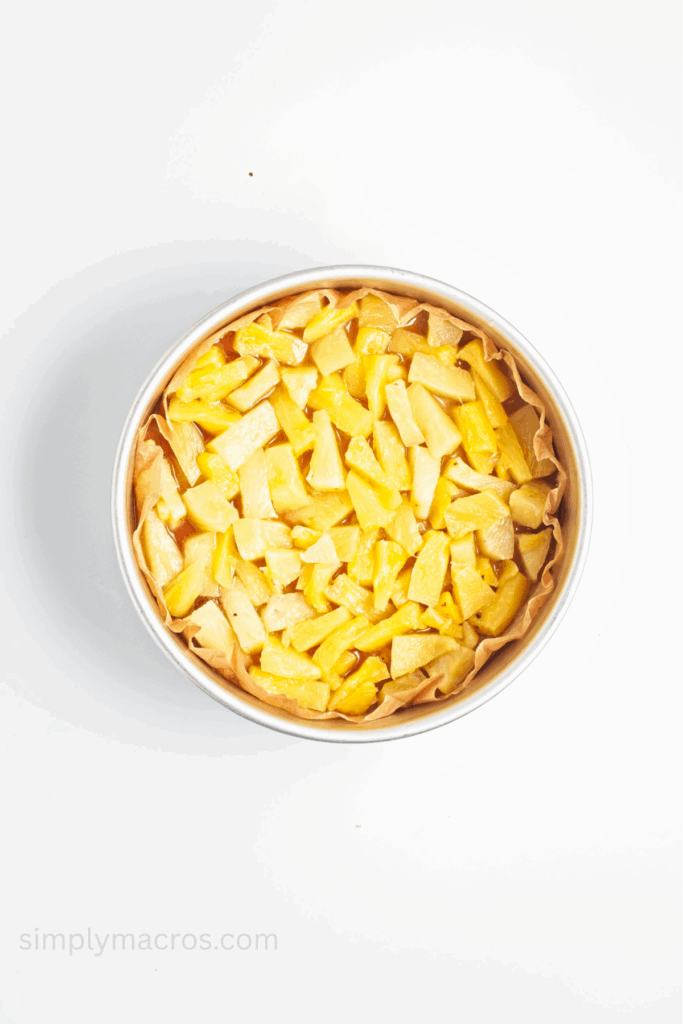 Pineapple chunks covering the caramel in the cake pan.